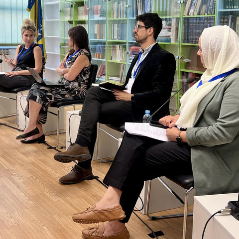 Four panelist for a talk are seated in front of a large bookcase. 